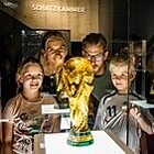 Eine Familie betrachtet einen der Pokale im Fußballmuseum.