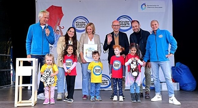 Dezernent Robert Voigtsberger und der kommissarische BIÖG-Leiter Dr. Johannes Nießen übergeben den Anerkennungspreis an die Leiterin der Kita Hunoldstraße im Beisein vieler Kinder