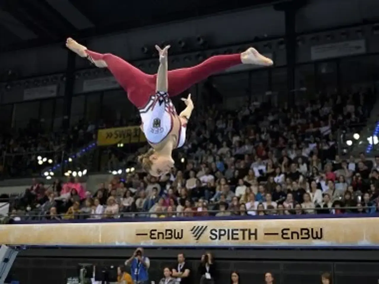 Sarah Voss auf dem Schwebebalken, frei schwebend, kopfüber im Spagat.