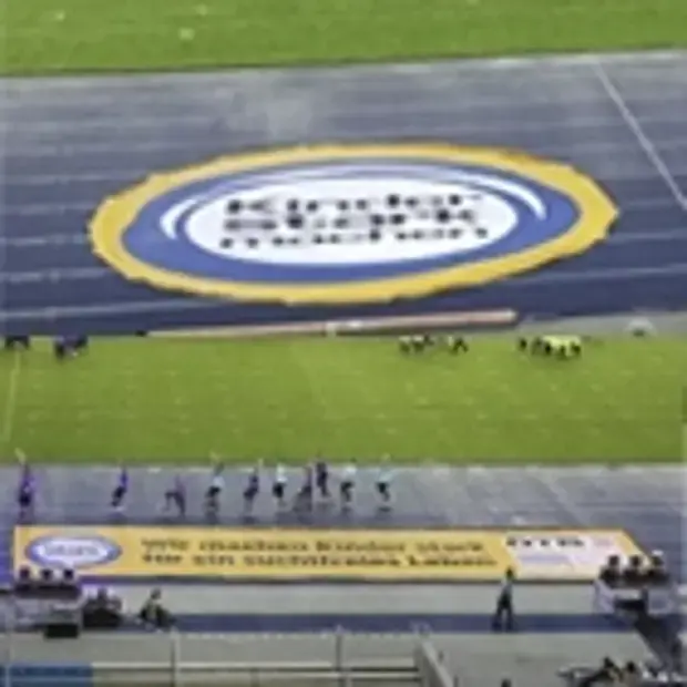 Oben großer runder Kinder stark machen Banner unten viele Kinder auf dem Fußballfeld