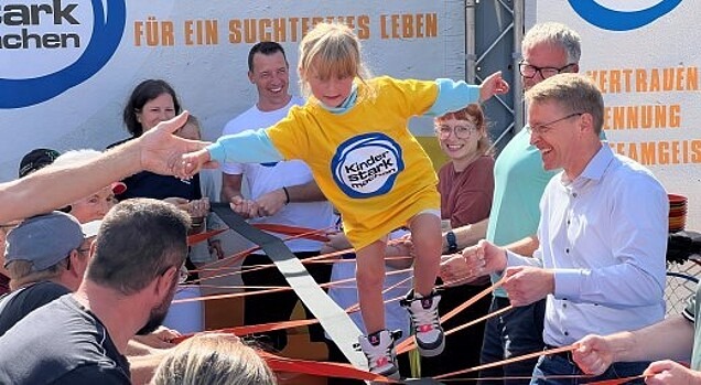 Dominik Klein mit hohem Besuch auf der Aktionsbühne - Gemeinsam spannen sie das Teambalancierband, über das es Mädchen balanciert.