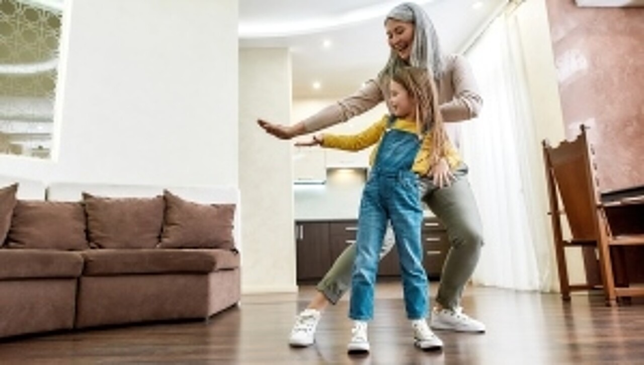 Großmutter und Enkelin tanzen im Wohnzimmer.
