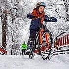 Ein Junge fährt Fahrrad im Schnee.