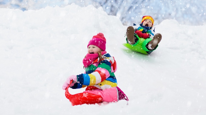 Zwei Kinder rodeln im Schnee