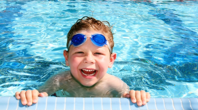 Kleiner Junge am Beckenrand im Schwimmbad