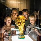 Eine Familie betrachtet einen der Pokale im Fußballmuseum.