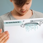 Ein Junge zeigt die PDF-Vorlage für die Warme Dusche mit einem Bild von einem Duschkopf, darunter viel Platz für positive Botschaften.
