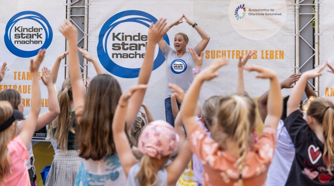 Singa tanzt auf der Aktionsbühne und viele Kinder davor mit ihr.