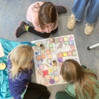Kinder sitzen um einen Spielplan und spielen "Party im Löwengehege"
