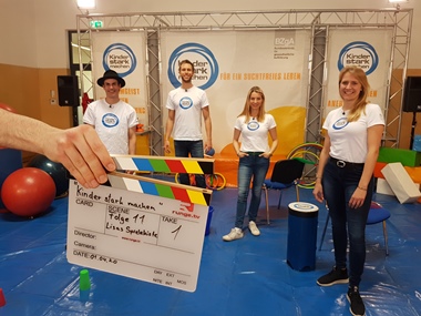 Vier Personen in „Kinder stark machen“-T-Shirts auf Aktionsbühne
