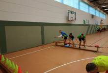 Kinder & Jugendliche stehen an einer Bank und werfen mit Frisbees auf Pylonen