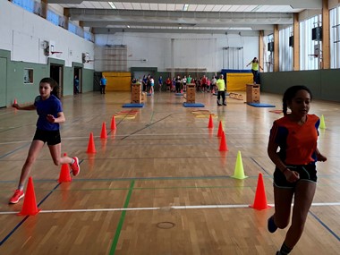 Kinder in Sporthalle rennen um Pylonen