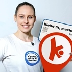 Sarah Voss zeigt ein Schild von einer Bewegungshaltestelle.